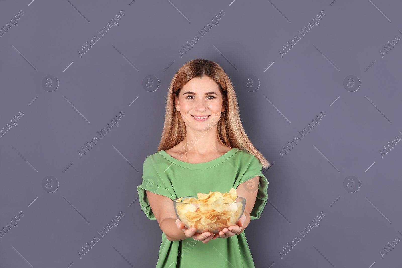 Photo of Woman with bowl of potato chips on grey background