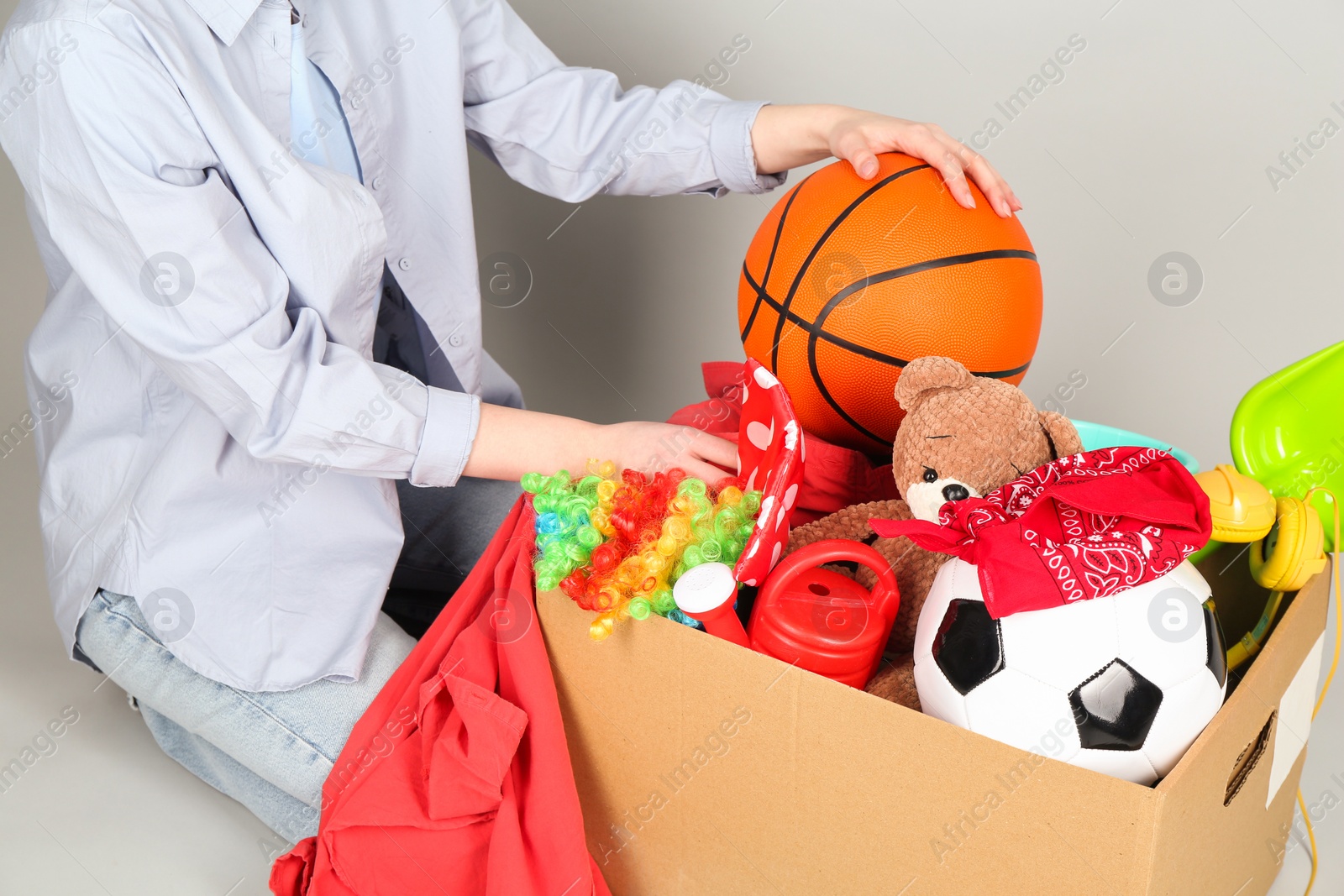 Photo of Woman with box of unwanted stuff on grey background, closeup