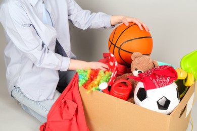 Photo of Woman with box of unwanted stuff on grey background, closeup