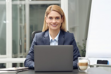 Woman working on laptop at black desk in office