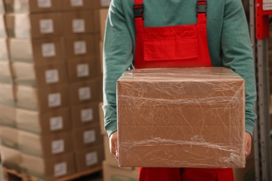 Photo of Worker with cardboard box in warehouse, closeup. Wholesaling