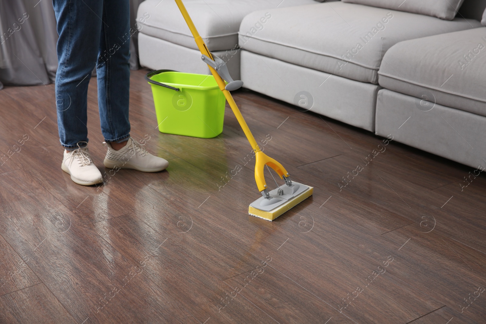 Photo of Woman cleaning parquet floor with mop indoors, closeup