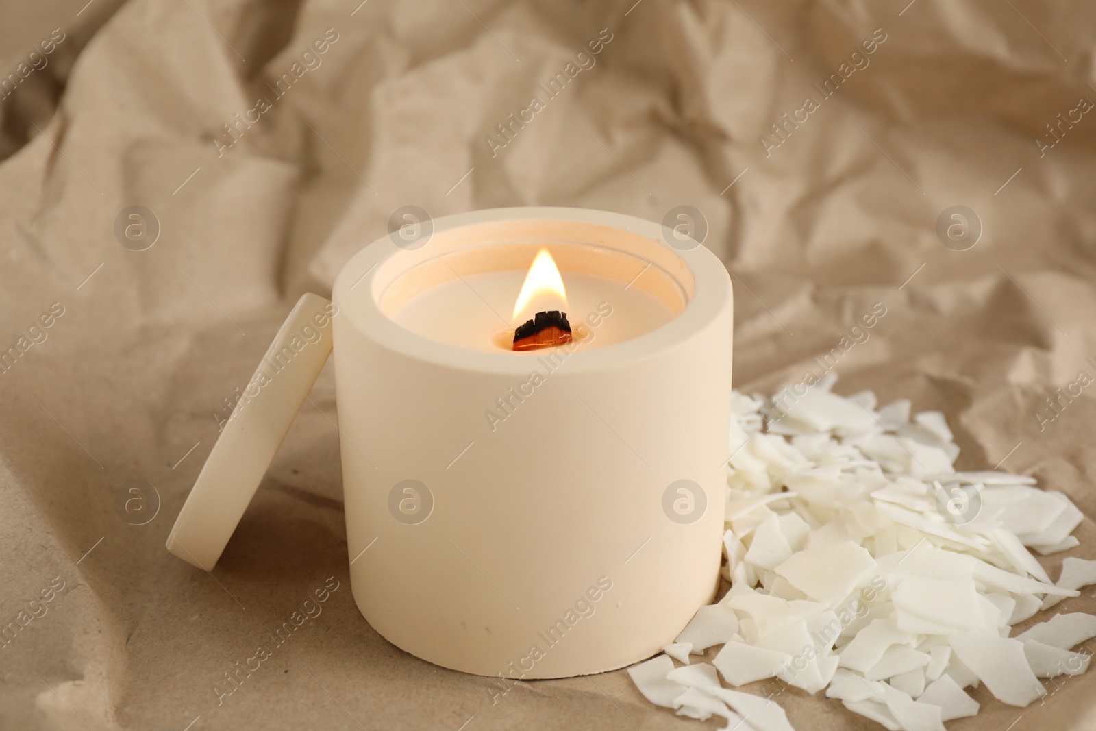 Photo of Burning soy candle and wax flakes on crumpled kraft paper