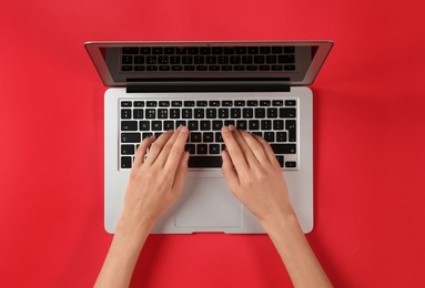 Woman using modern laptop at color table, top view