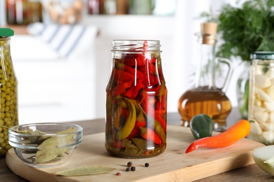 Photo of Jar with pickled chili peppers on wooden table indoors