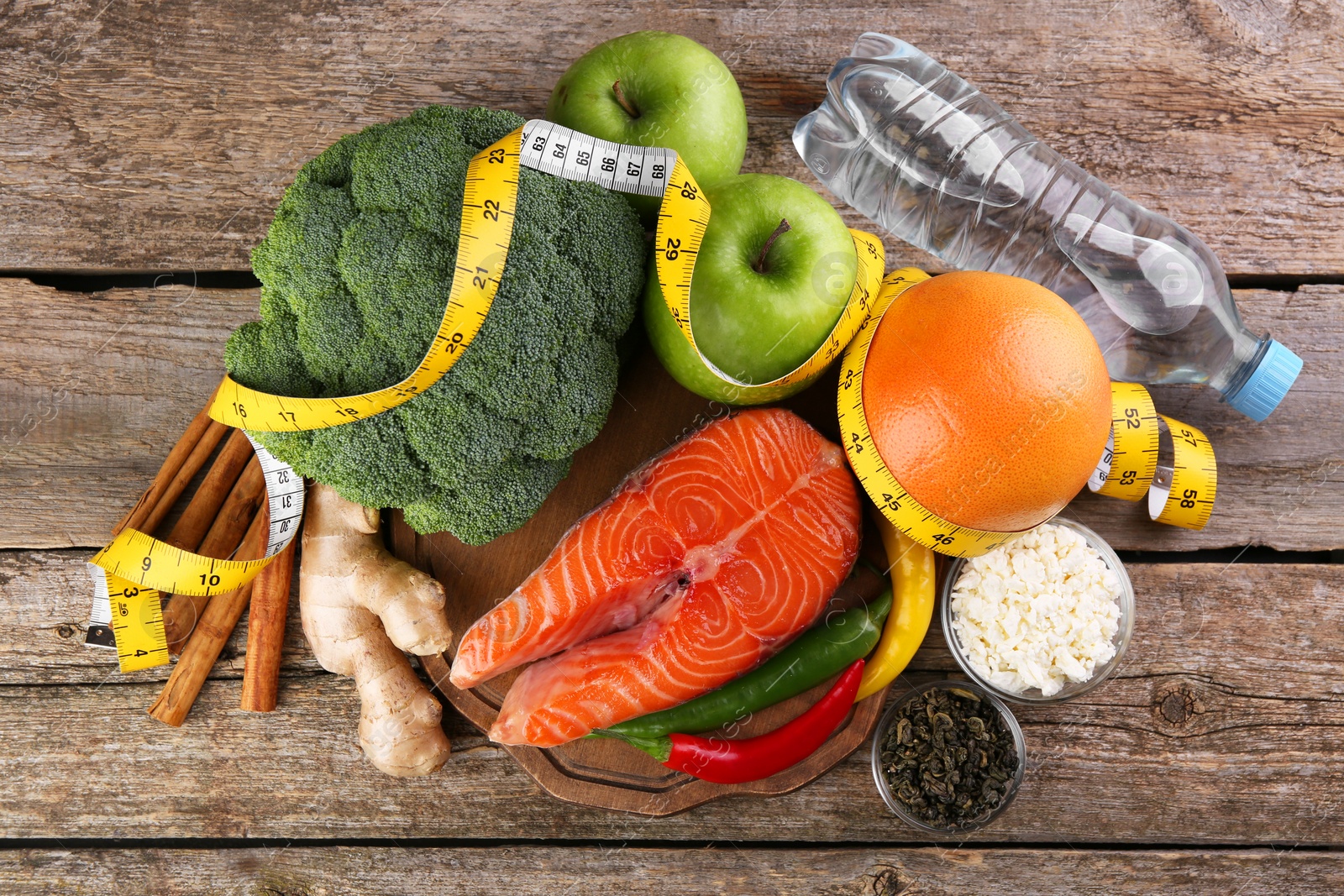 Photo of Metabolism. Different food products and measuring tape on wooden table, flat lay