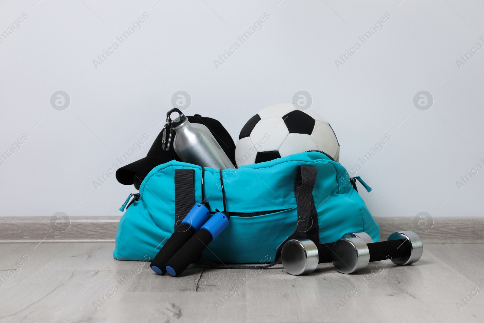 Photo of Stylish sports bag and different gym stuff on wooden floor indoors