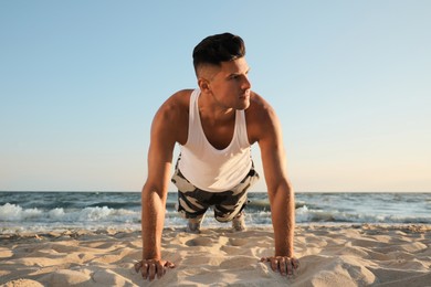 Photo of Sporty man doing plank on sandy beach