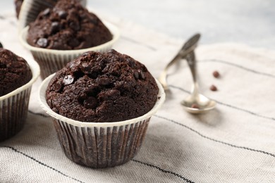 Tasty chocolate muffins and cloth on table, closeup. Space for text