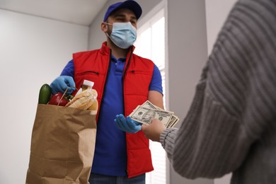 Young woman giving tips to courier indoors, closeup