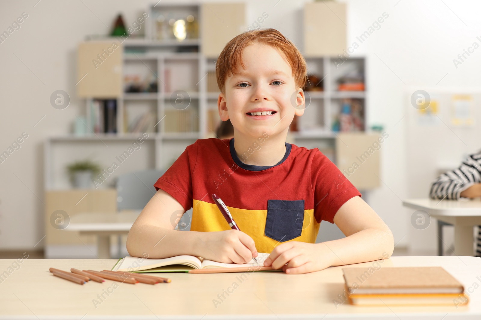 Photo of Portrait of smiling little boy studying in classroom at school