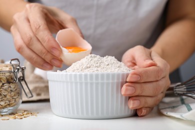 Photo of Woman cooking oatmeal dough at white table in kitchen, closeup