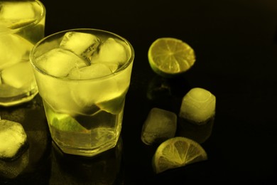Photo of Shot glassesvodka with ice cubes and lime slices on dark background