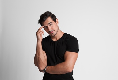 Photo of Portrait of handsome young man in black t-shirt on grey background