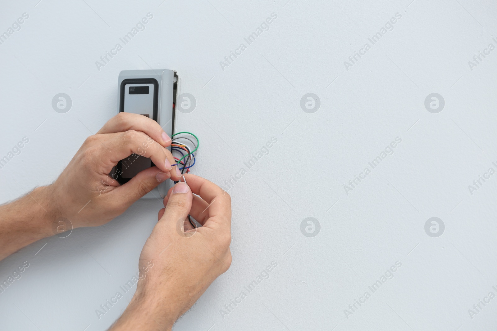 Photo of Young male technician installing alarm system indoors