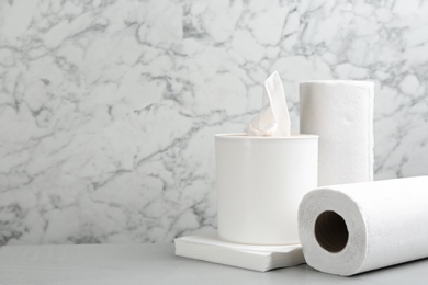 Clean napkins, box with tissues and rolls of paper towels on light table, space for text