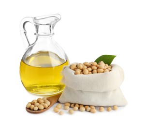 Glass jug of oil and soybeans on white background