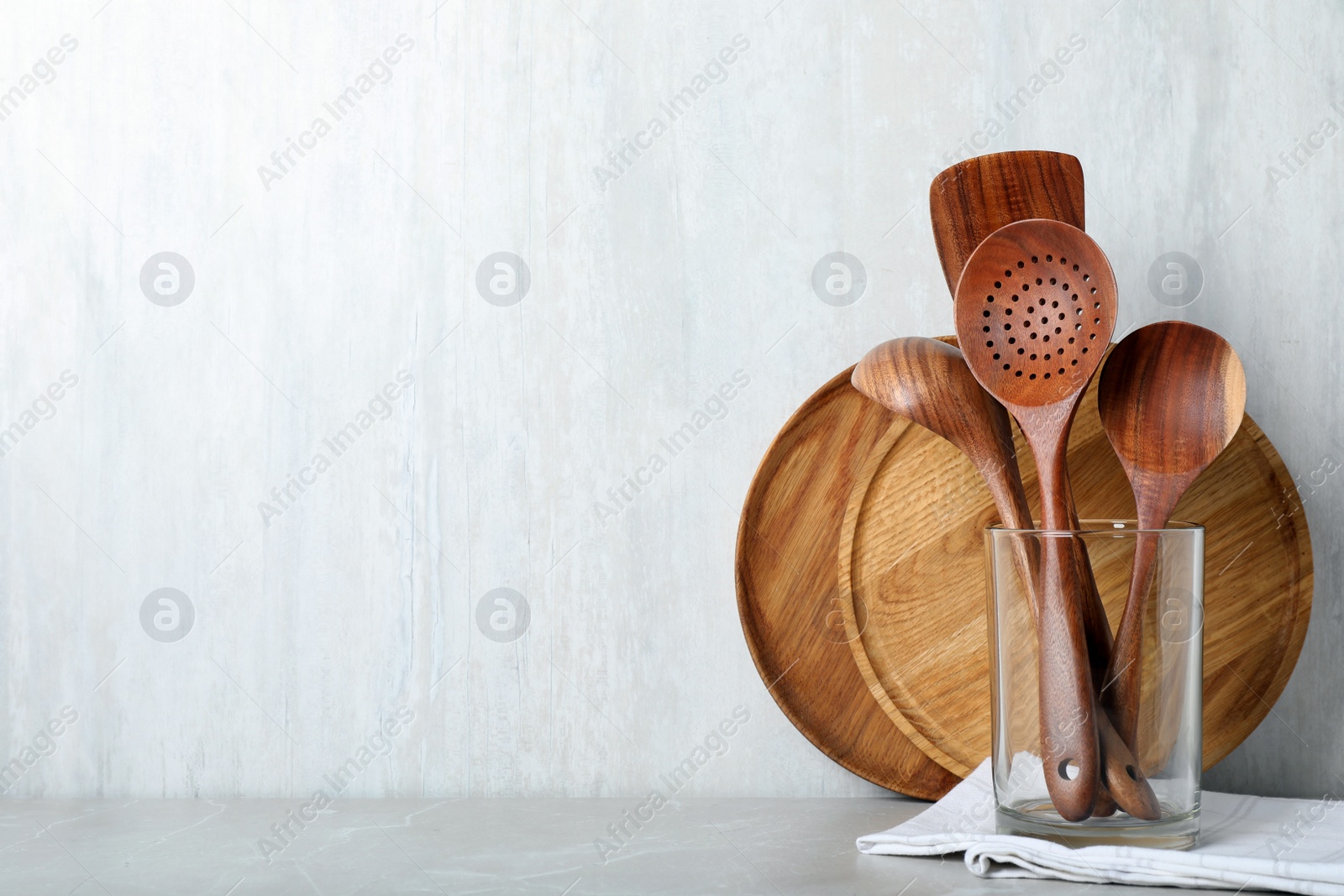 Photo of Set of wooden kitchen utensils and plates on light grey table. Space for text