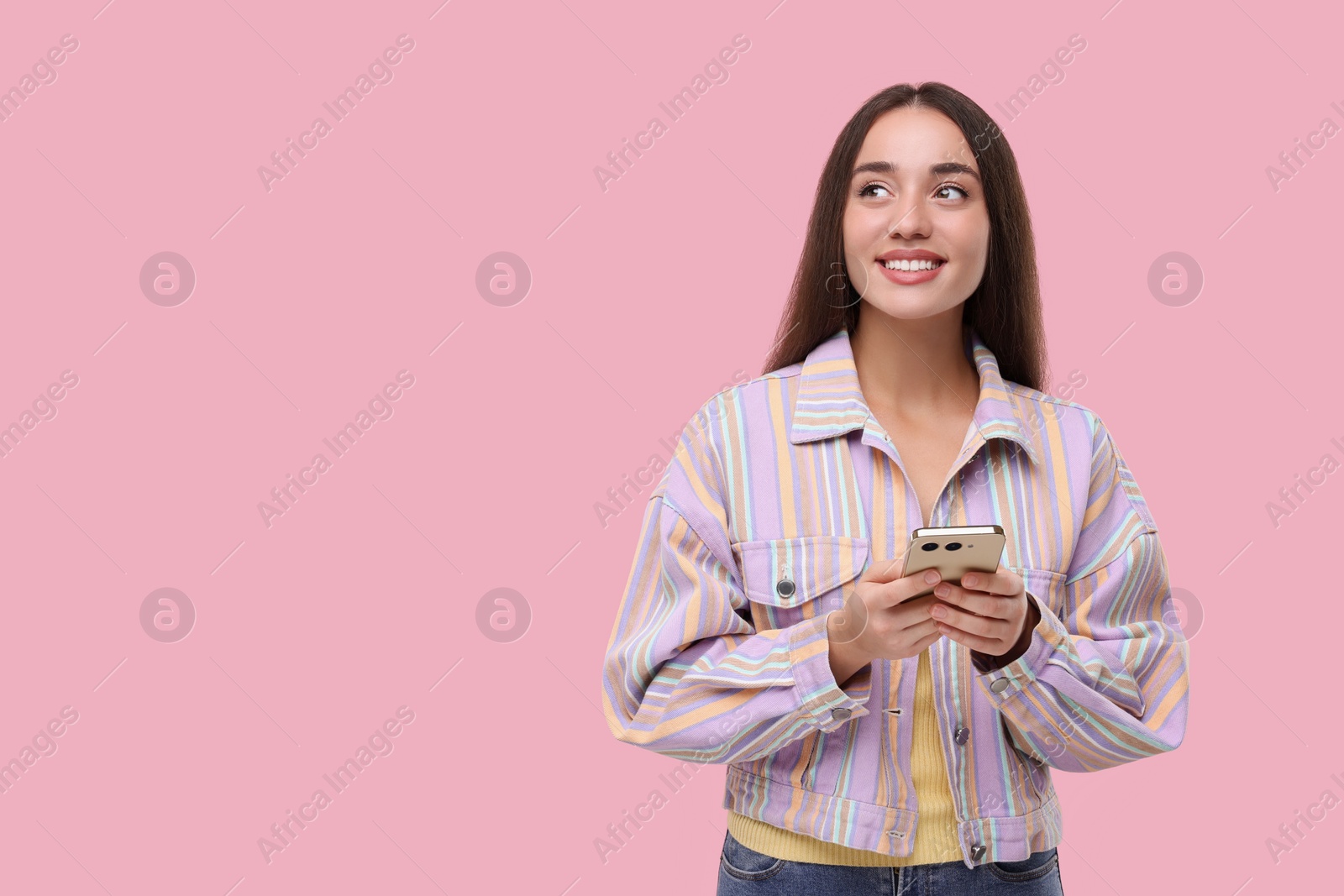 Photo of Happy woman sending message via smartphone on pink background, space for text