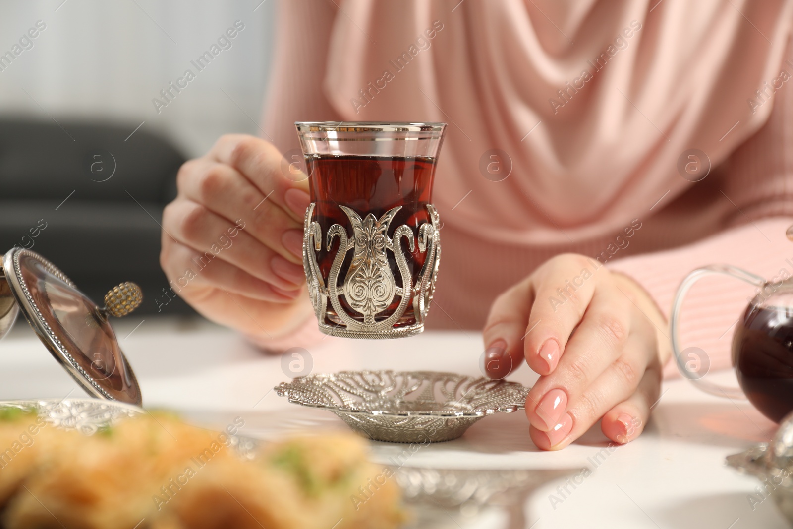 Photo of Woman with cup of delicious Turkish tea at white table, closeup
