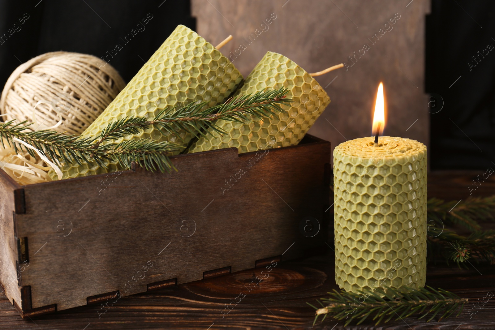 Photo of Stylish elegant beeswax candles with spruce branches and twine on wooden table