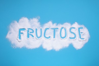 Photo of Word Fructose made of powder on light blue background, flat lay