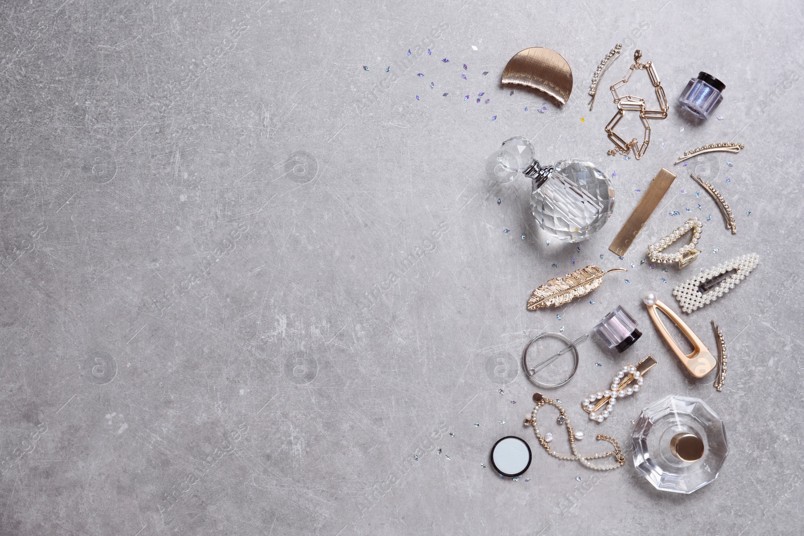 Photo of Flat lay composition with stylish hair clips and perfumes on grey background. Space for text