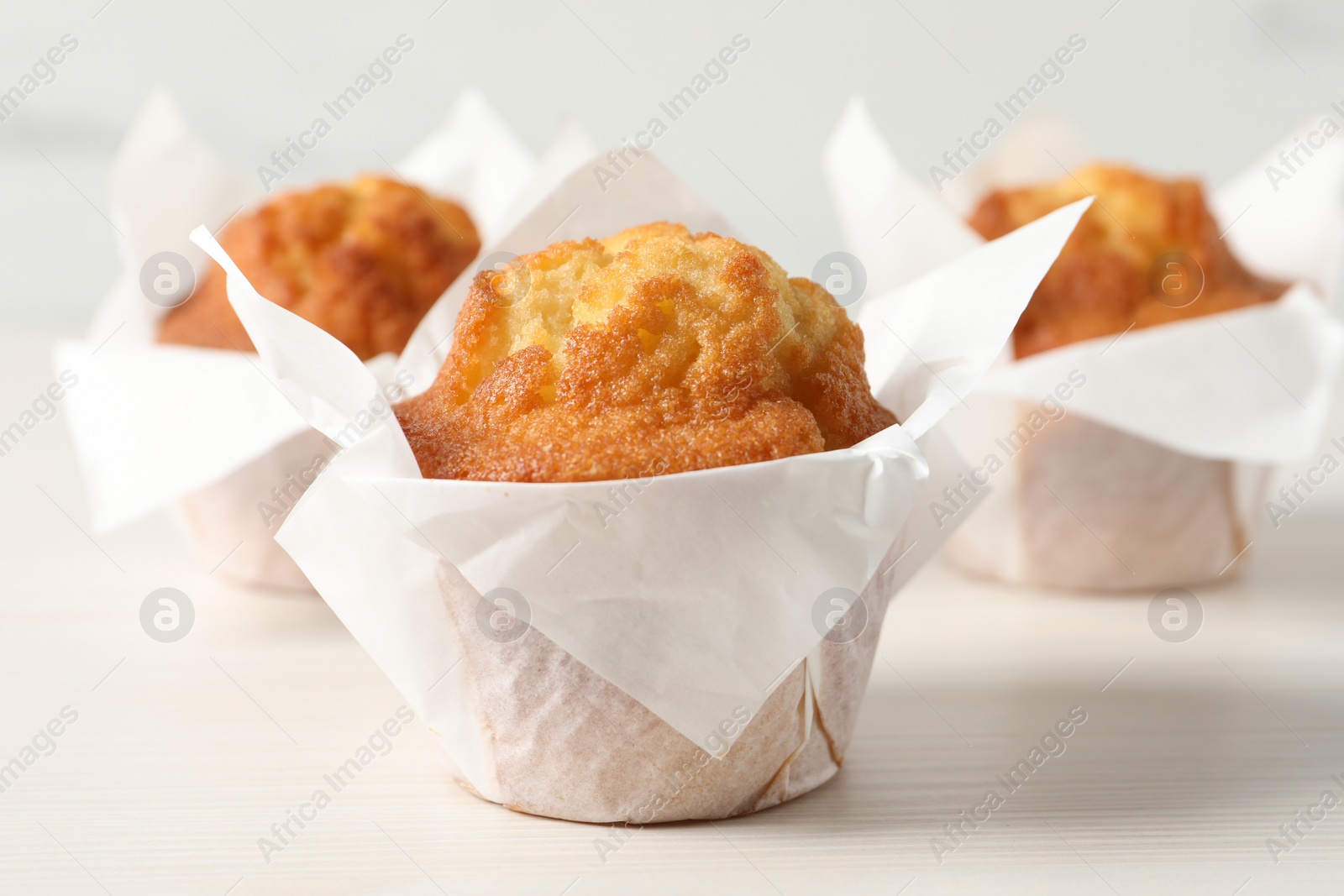 Photo of Tasty muffins on white wooden table, closeup. Fresh pastry