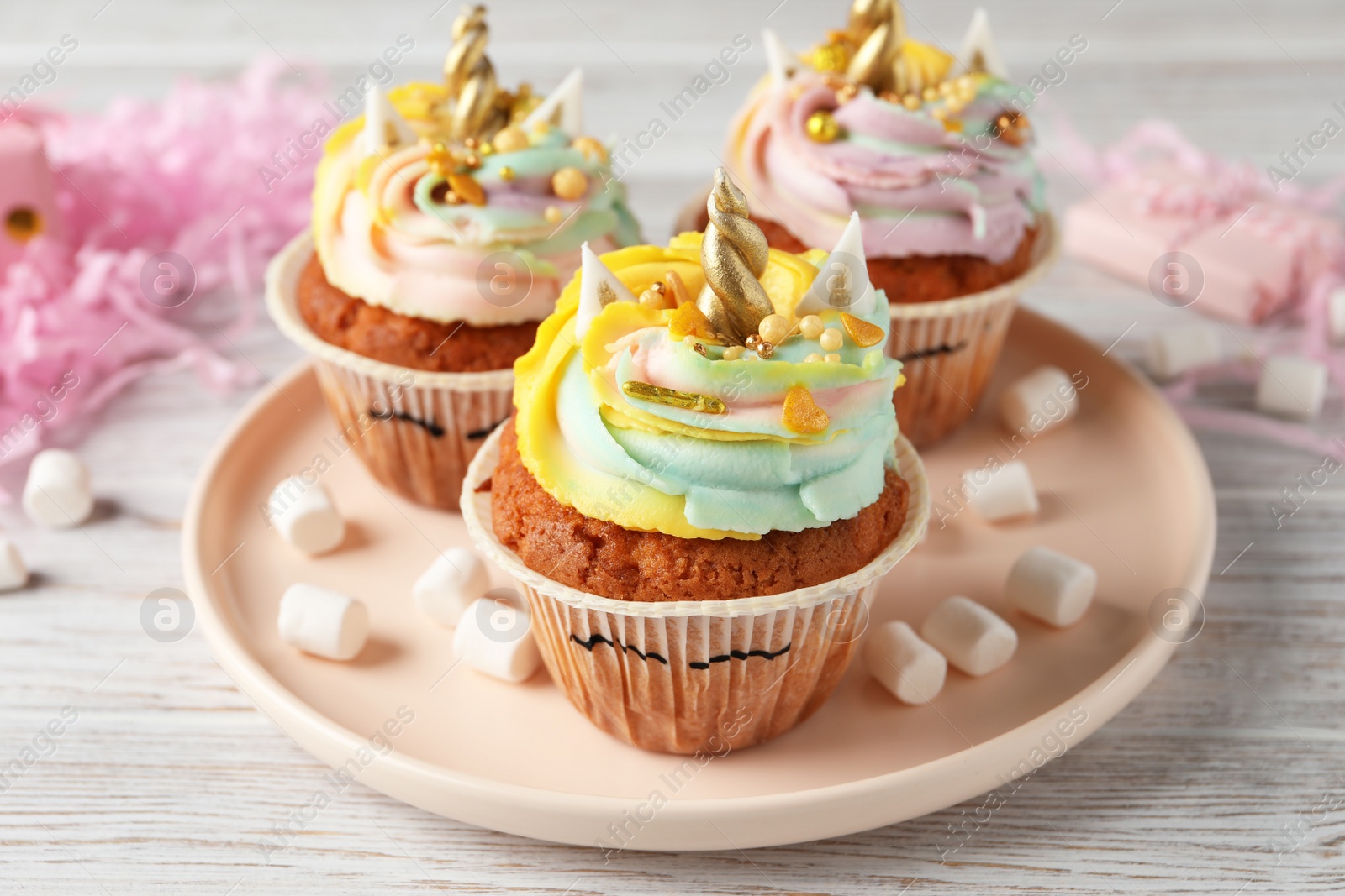 Photo of Cute sweet unicorn cupcakes on white wooden table