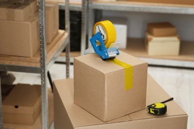 Photo of Taping cardboard box with adhesive tape dispenser indoors