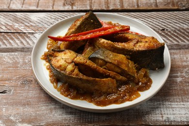 Photo of Tasty Indian fish curry on wooden table, closeup