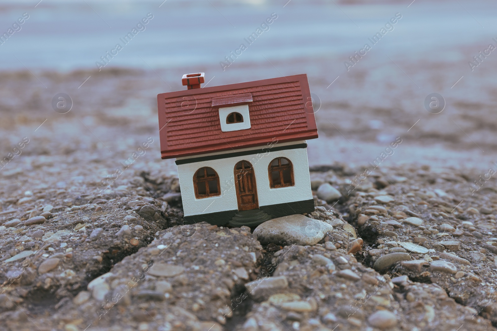 Photo of House model in cracked asphalt. Earthquake disaster