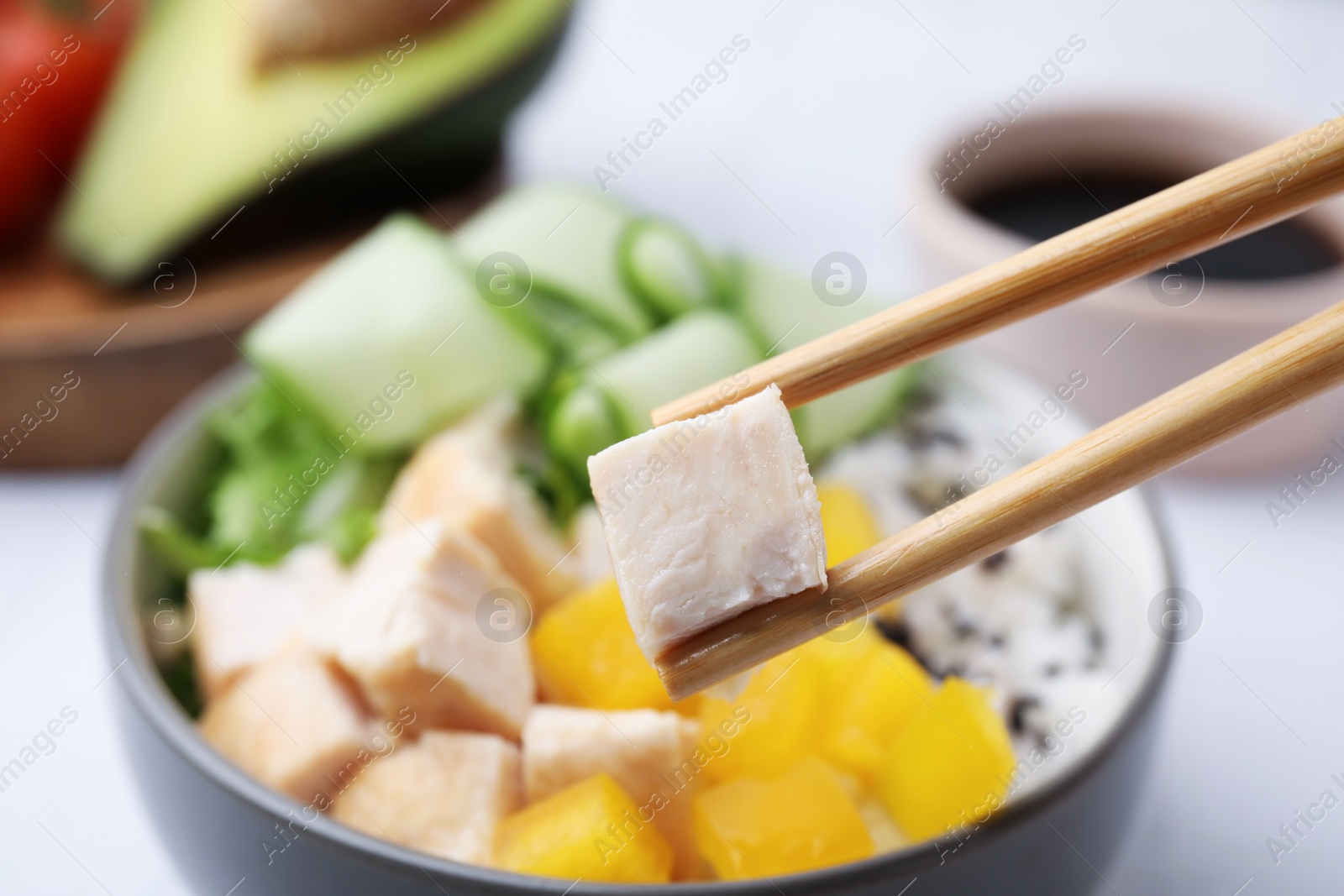Photo of Chopsticks with meat over delicious poke bowl , closeup