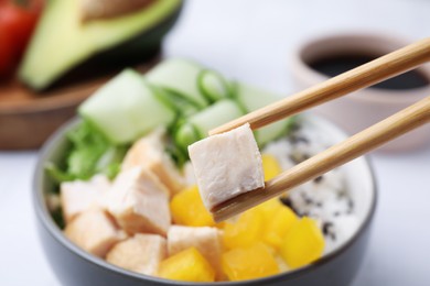 Chopsticks with meat over delicious poke bowl , closeup