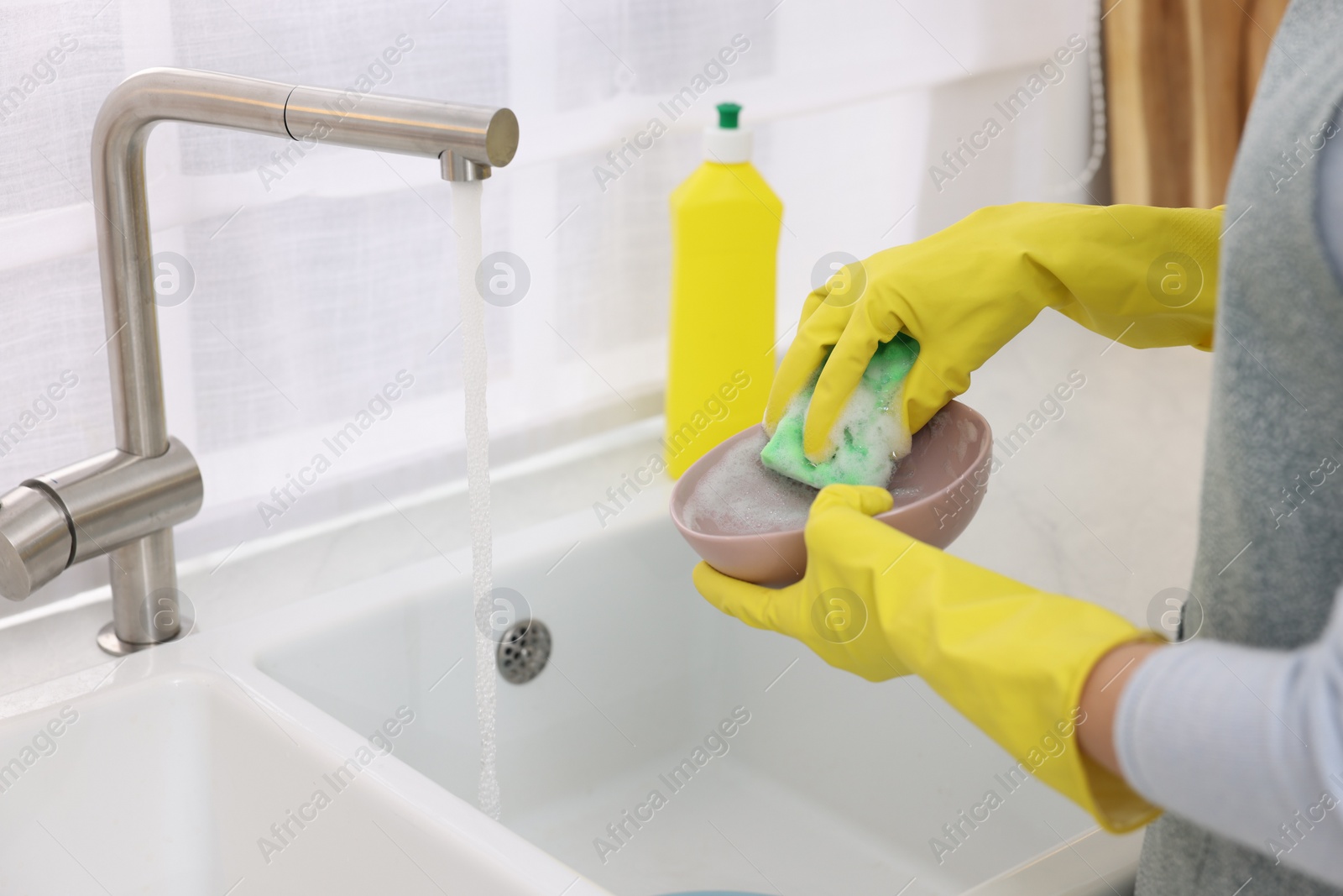 Photo of Woman washing plate above sink in modern kitchen, closeup