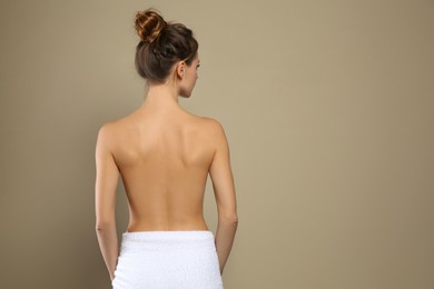 Back view of woman with perfect smooth skin on beige background, space for text. Beauty and body care