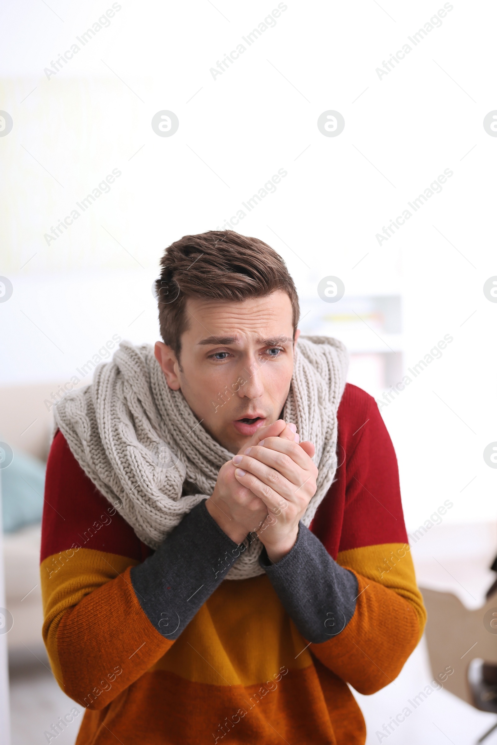 Photo of Sad young man suffering from cold on blurred background