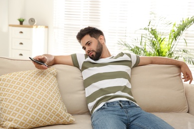 Photo of Lazy young man watching TV on sofa at home