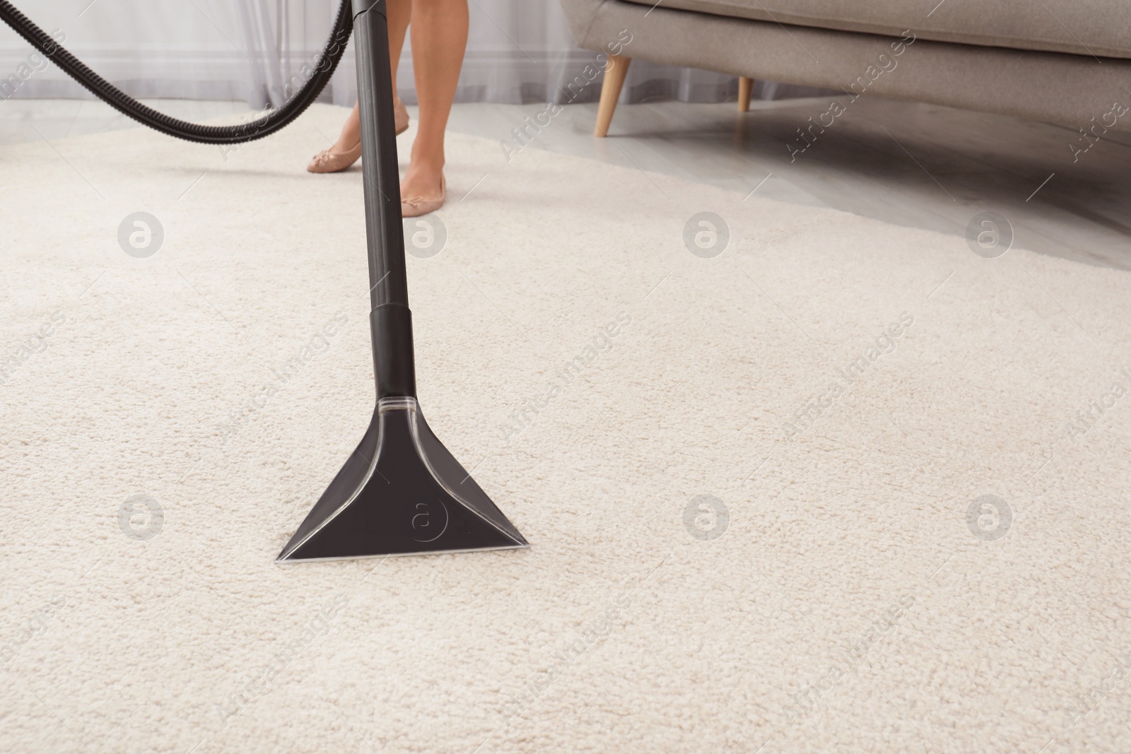 Photo of Woman removing dirt from carpet with vacuum cleaner indoors, closeup. Space for text