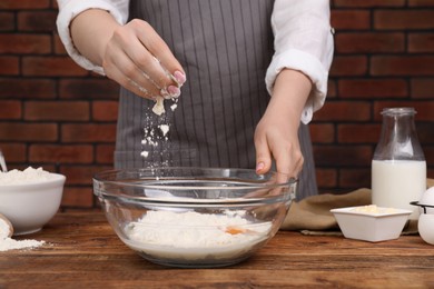 Preparing tasty baklava. Woman adding flour into bowl at wooden table, closeup