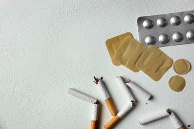 Photo of Nicotine patches, pills and broken cigarettes on white background, flat lay. Space for text