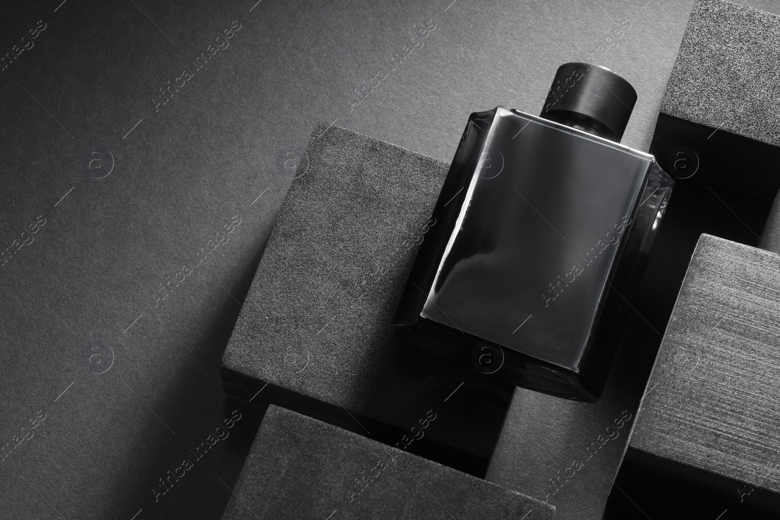 Photo of Stylish presentation of luxury men`s perfume in bottle on black background, above view. Space for text