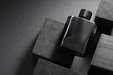 Photo of Stylish presentation of luxury men`s perfume in bottle on black background, above view. Space for text