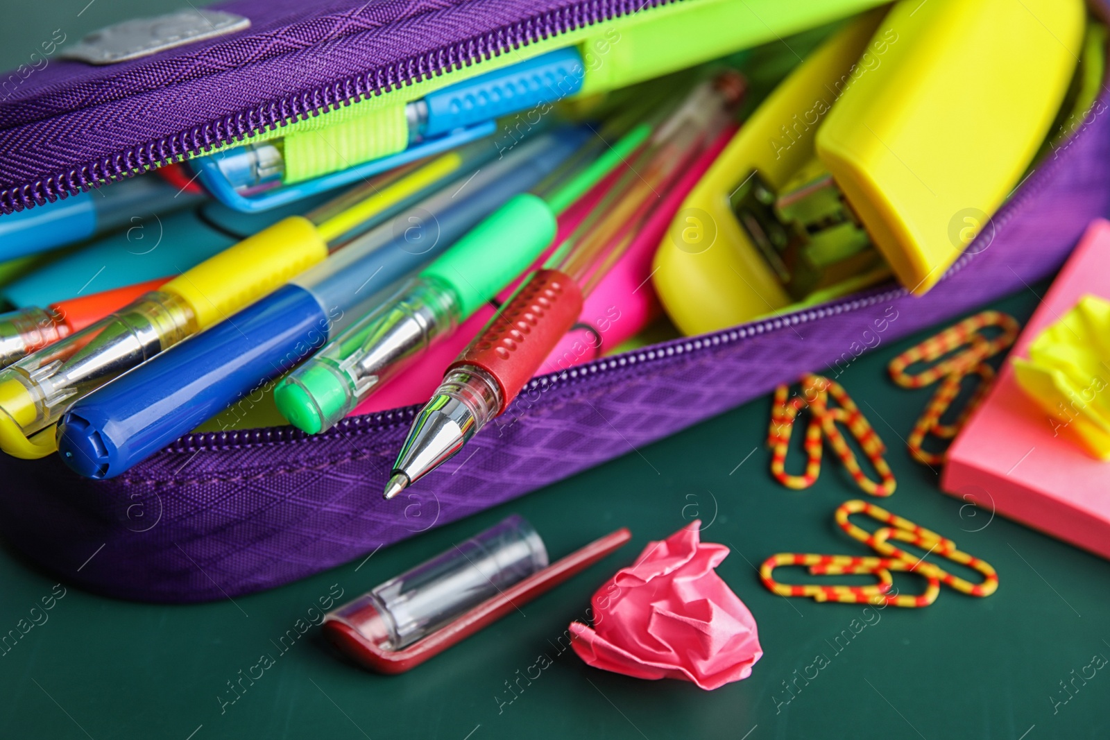 Photo of Different colorful stationery on chalkboard surface. Back to school