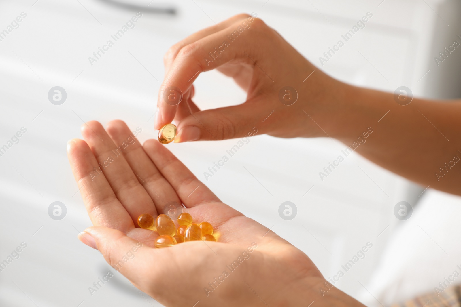 Photo of African-American woman with vitamin capsules at home, closeup