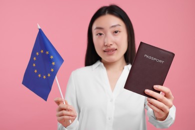 Immigration to European Union. Woman with passport and flag on pink background, selective focus