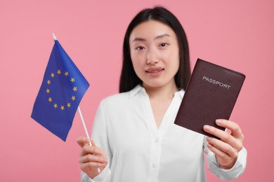 Photo of Immigration to European Union. Woman with passport and flag on pink background, selective focus