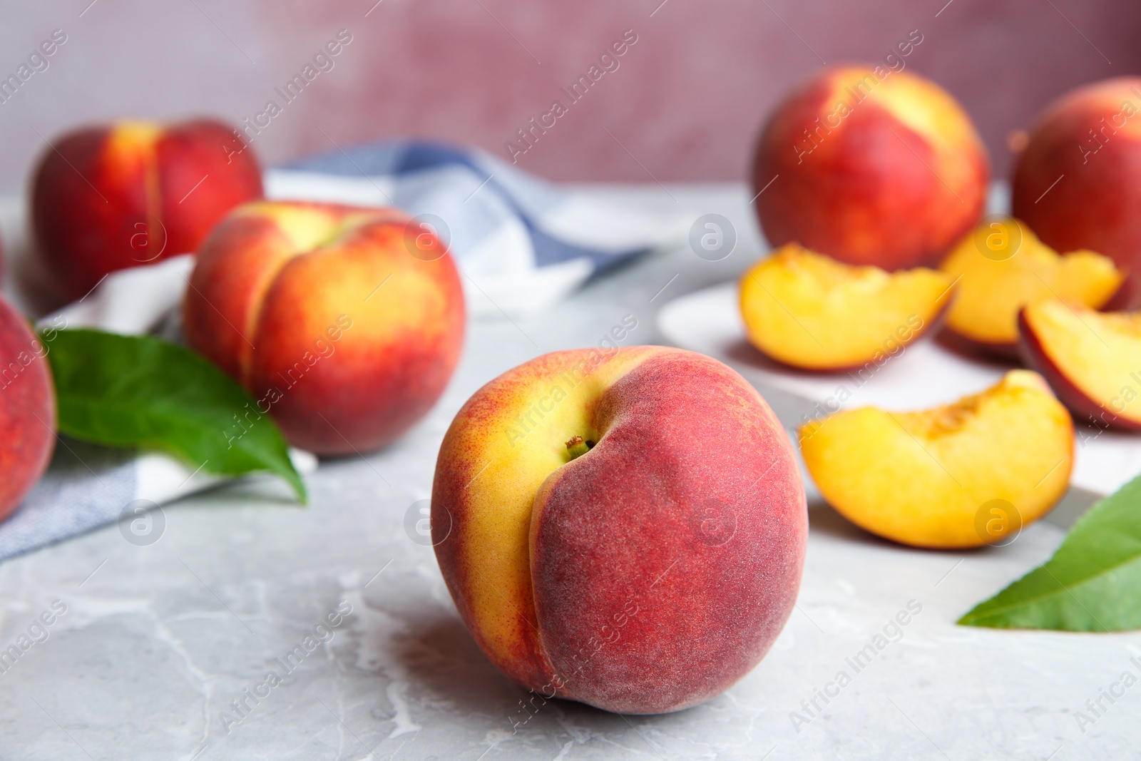 Photo of Cut and whole juicy peaches and leaves on marble table