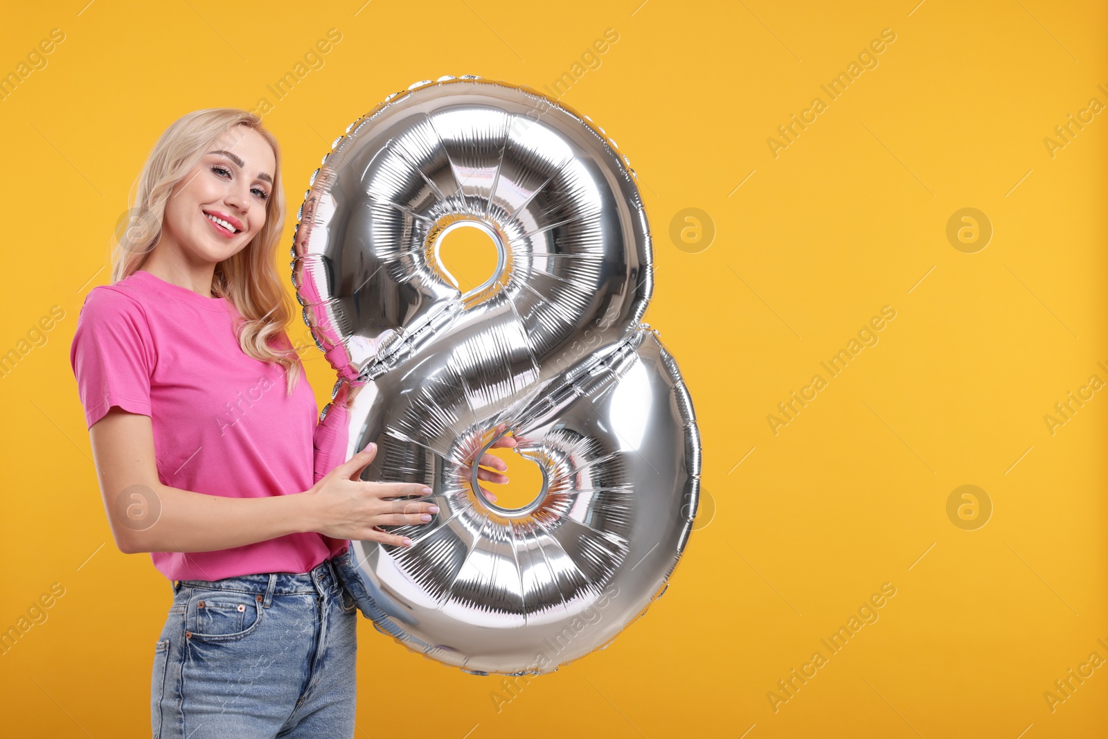 Photo of Happy Women's Day. Charming lady holding balloon in shape of number 8 on orange background