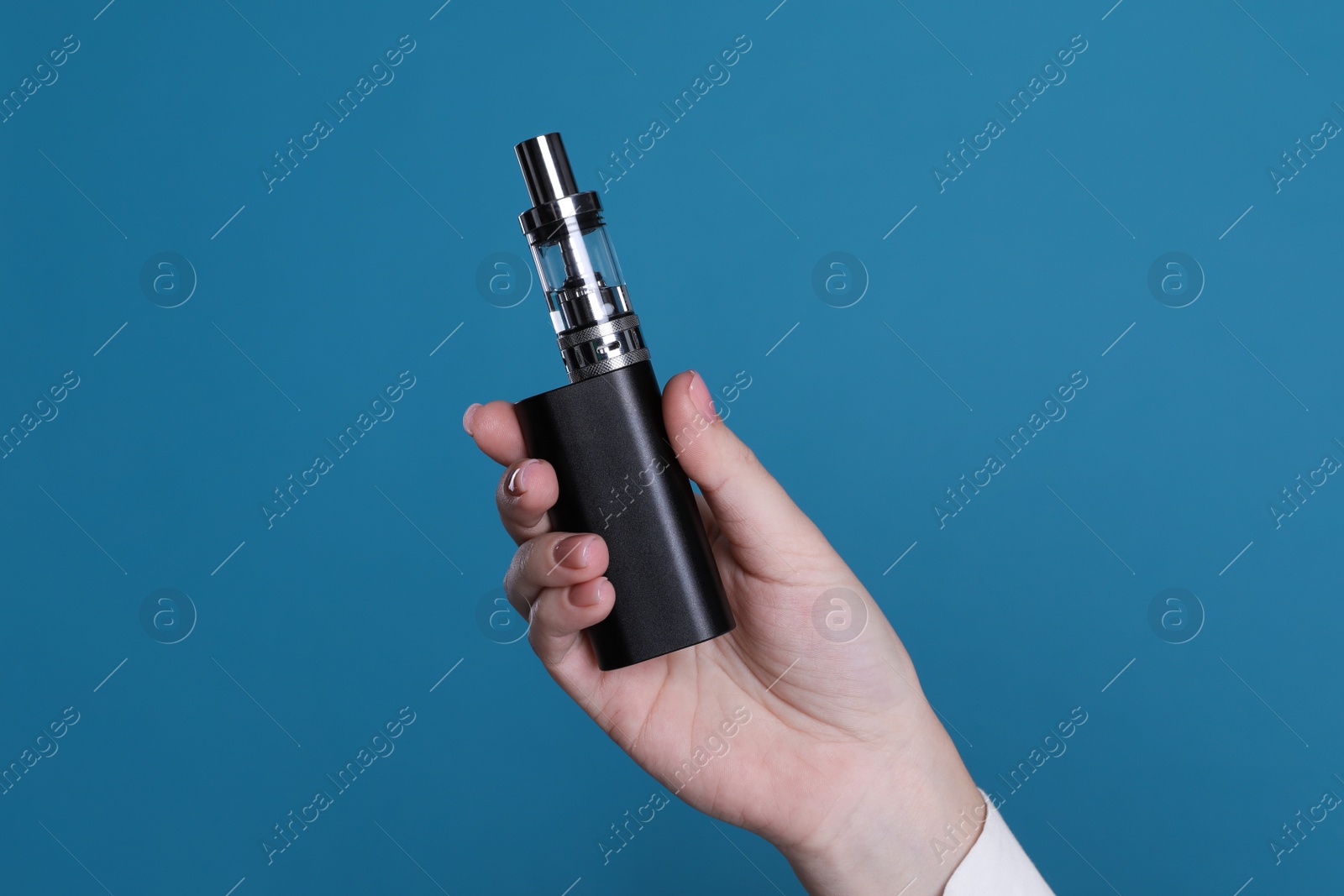 Photo of Woman holding electronic cigarette on light blue background, closeup